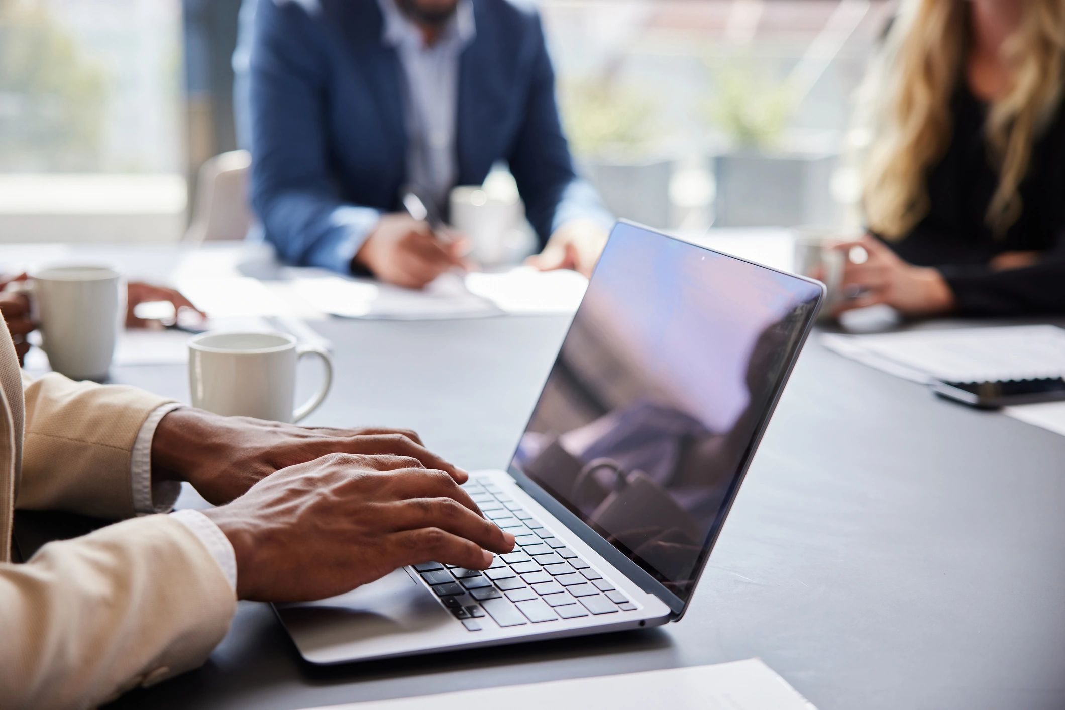 People browsing an online marketplace on a laptop during a meeting